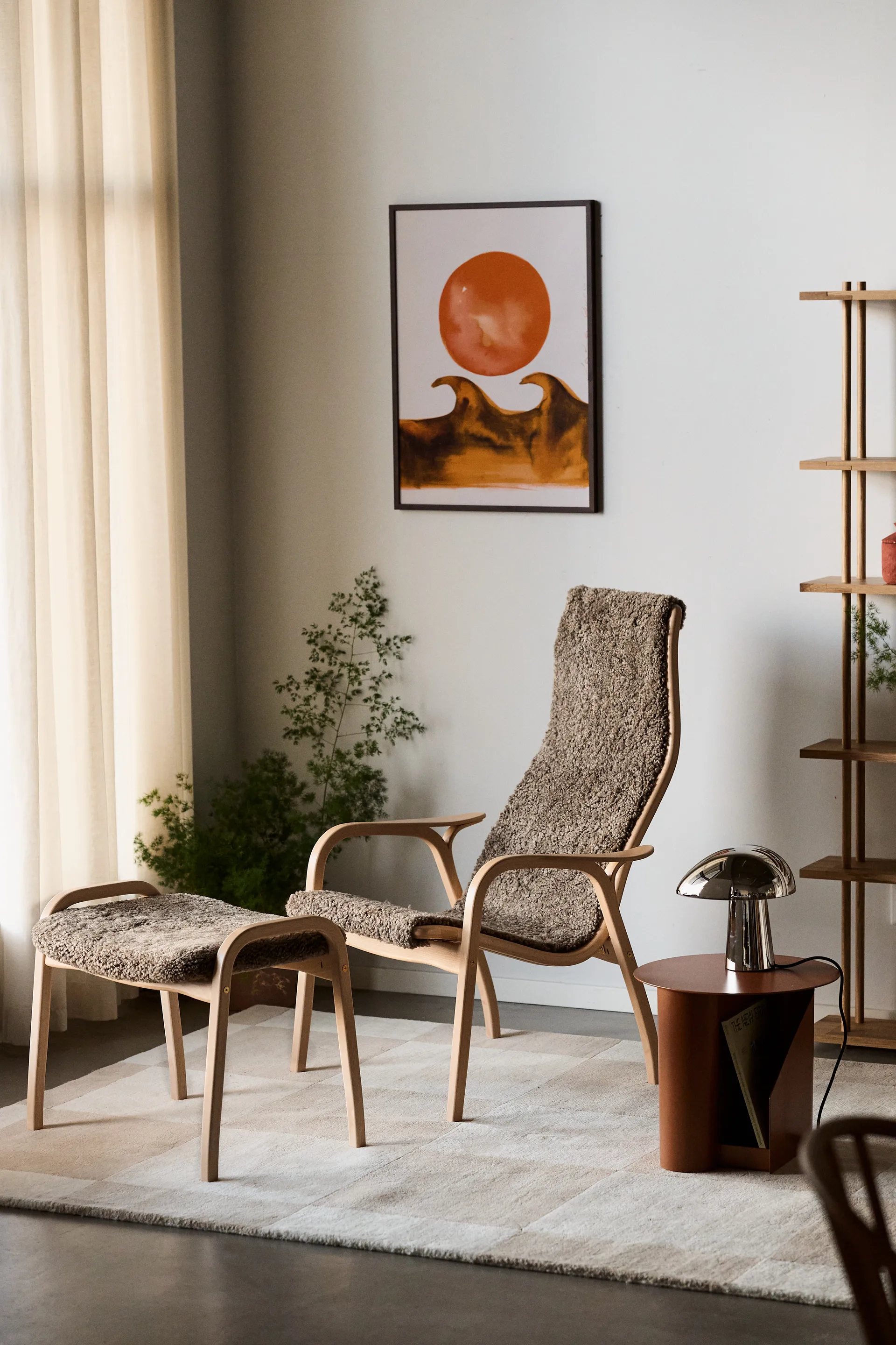 A cozy living space with a light wood armchair and ottoman with brown textured upholstery, a chrome lamp, and abstract art.
