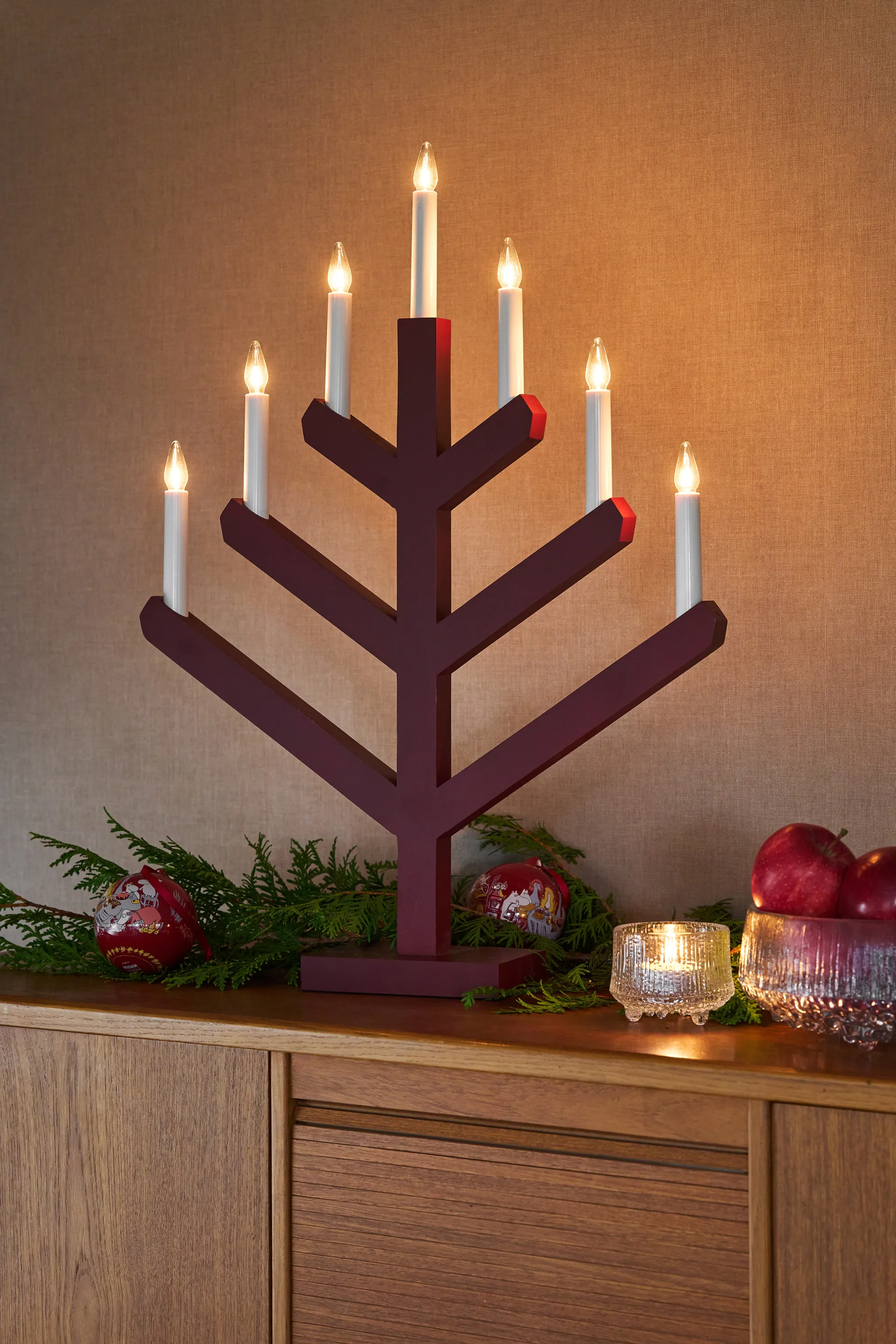 Burgundy wooden electric candelabra with seven white candles in a branch pattern on a wooden sideboard.