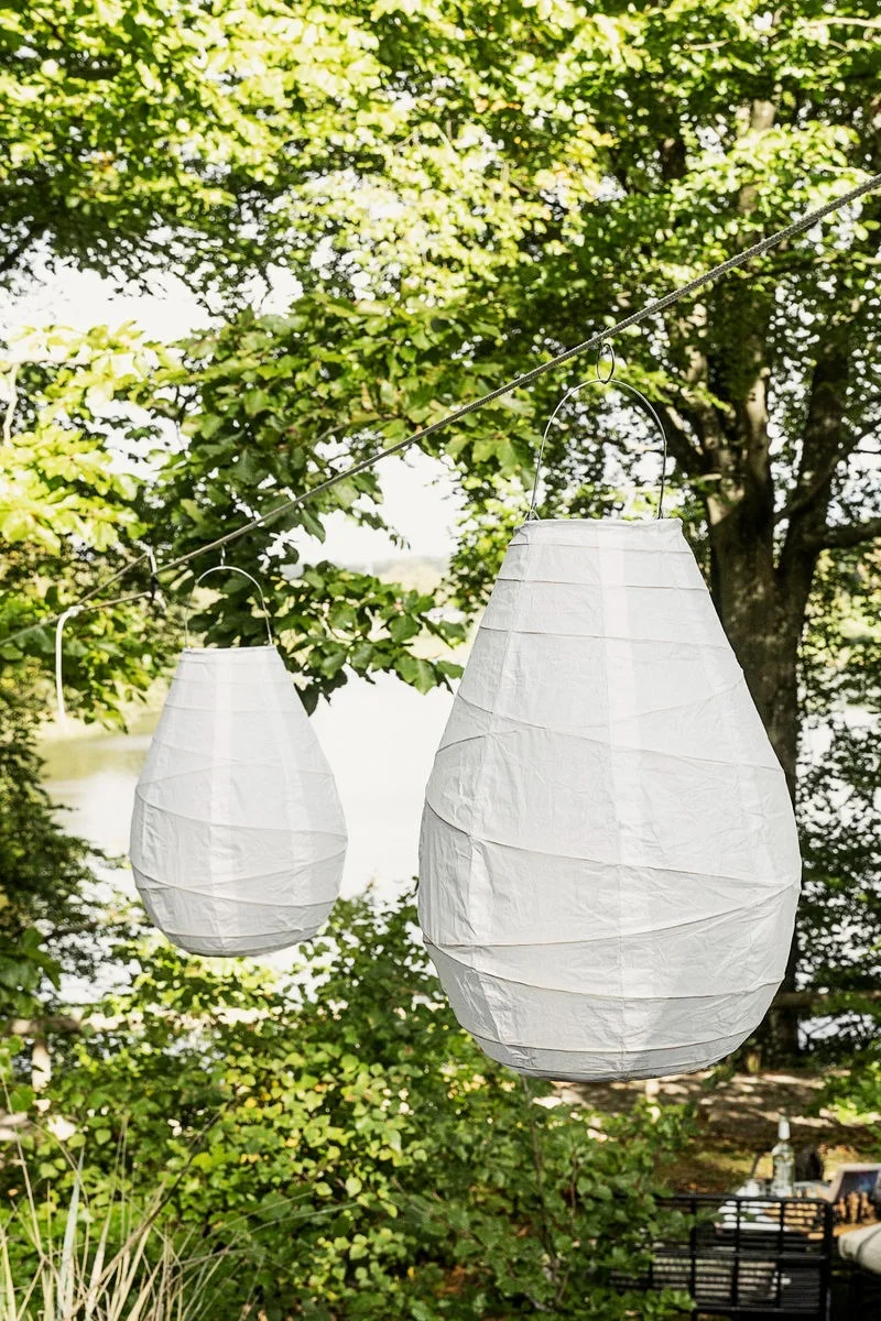 A crayfish party in Sweden: Two Drop paper lanterns from House Doctor hanging in a garden.