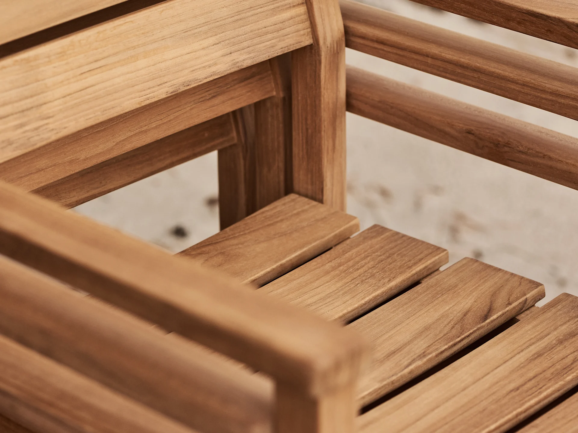 Close-up of the light brown wooden slats of a chair or bench, showing the natural wood grain.
