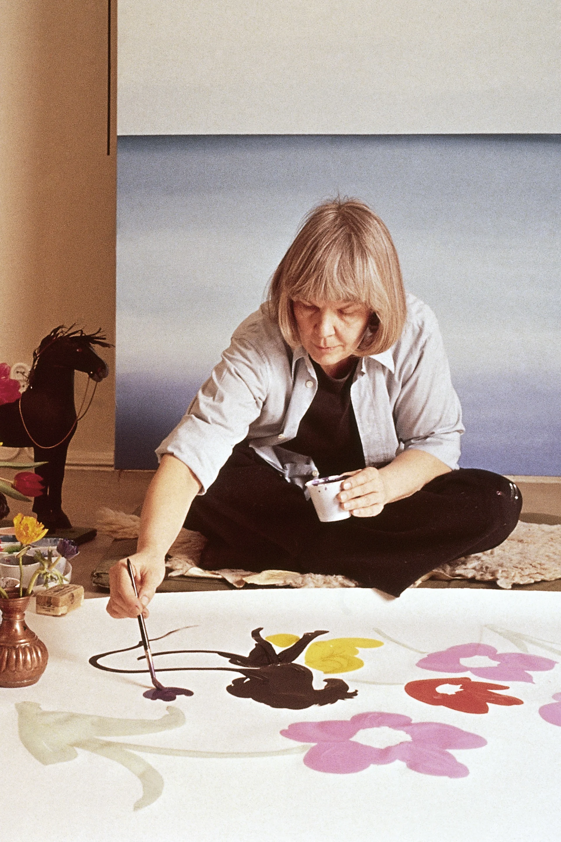 Maija Isola sits on the floor painting the famous Unikko pattern.