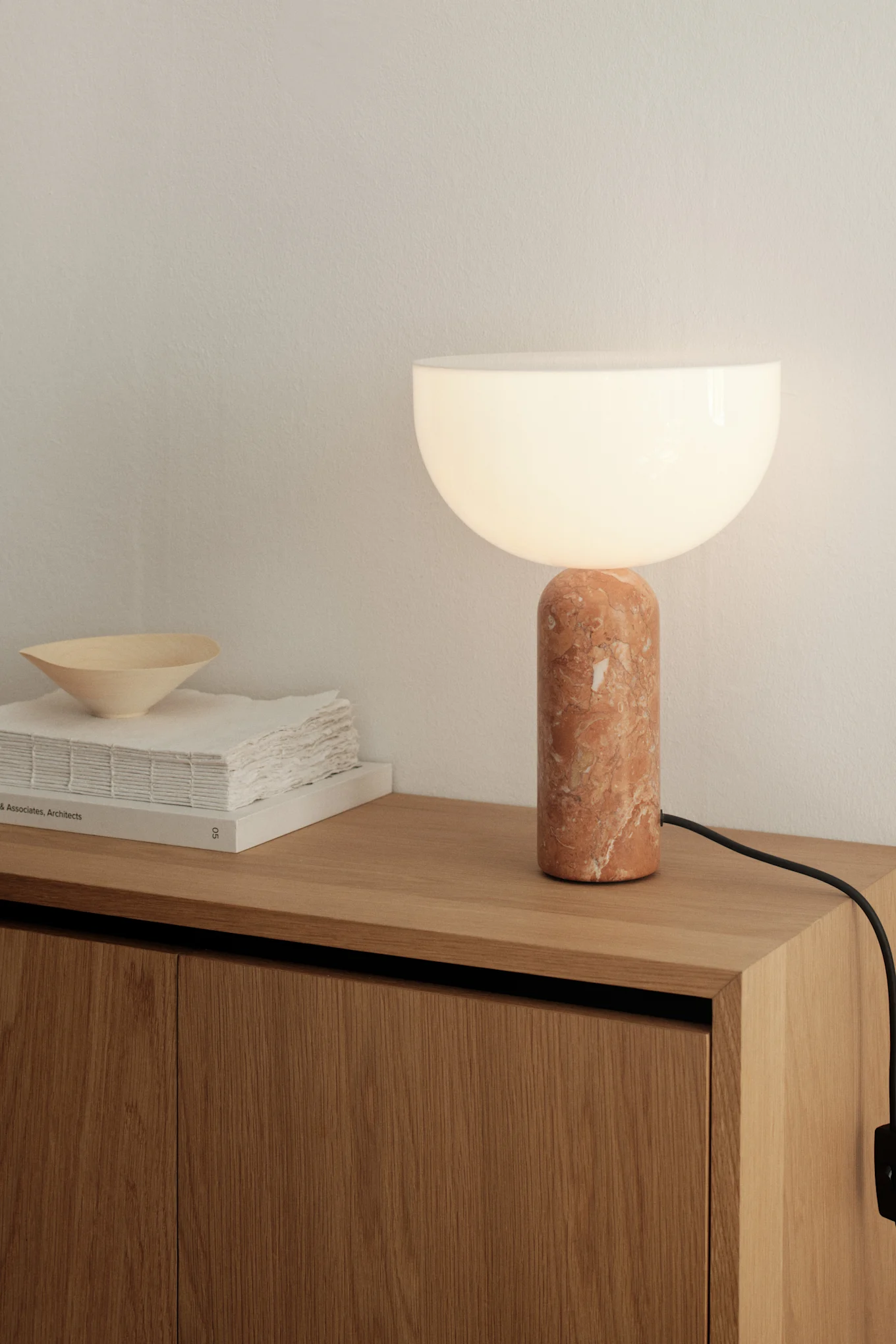 Layer your dining room lighting ideas. Here you see the Picasso table lamp in beige from Belid standing on a side table. 
