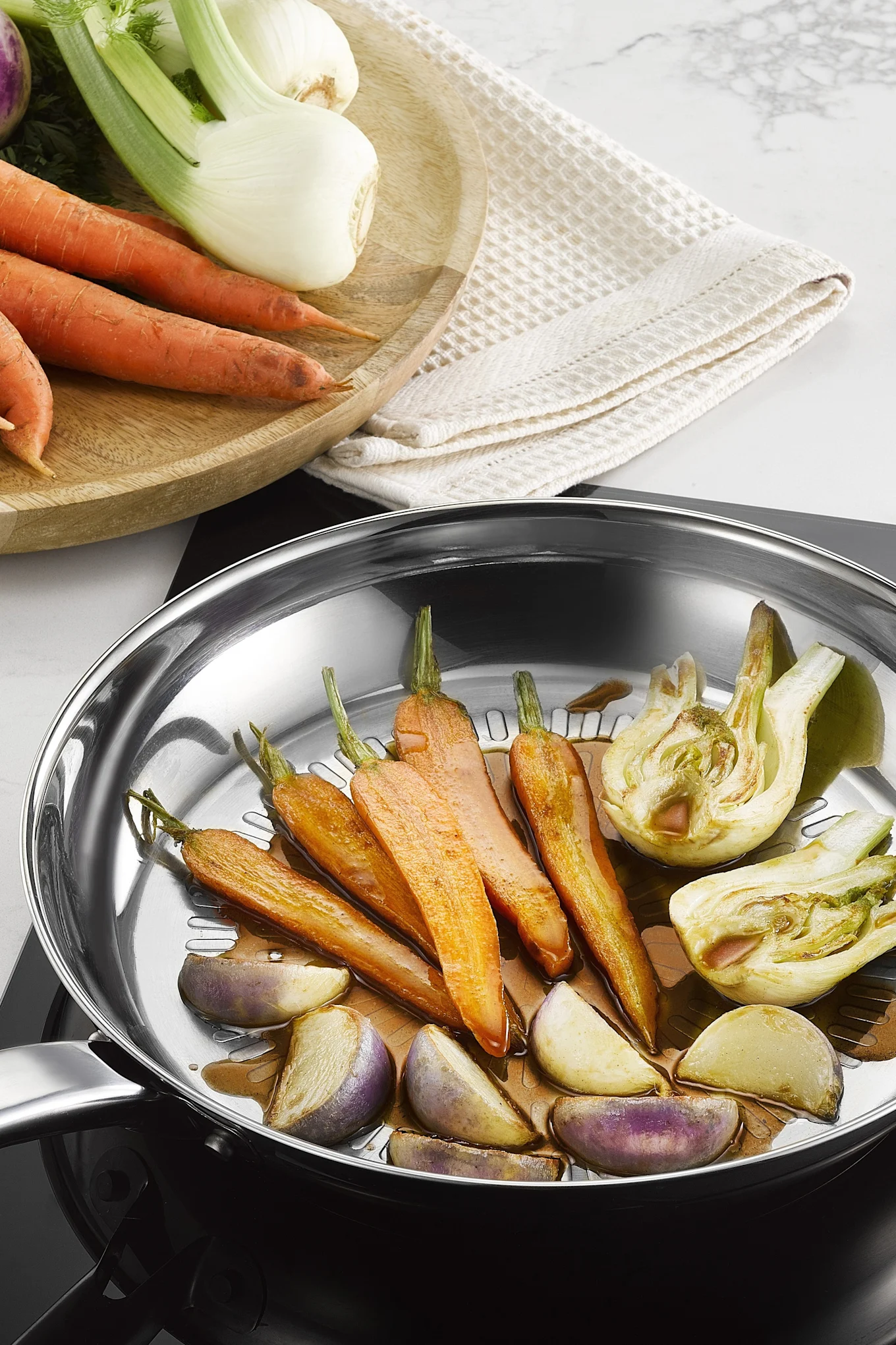 Various vegetables are fried in the stainless steel Intuition Techdome pan from Tefal.