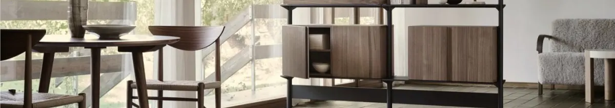Wooden dining table and chairs, a dark shelving unit with wood cabinets, and a light grey fuzzy armchair.