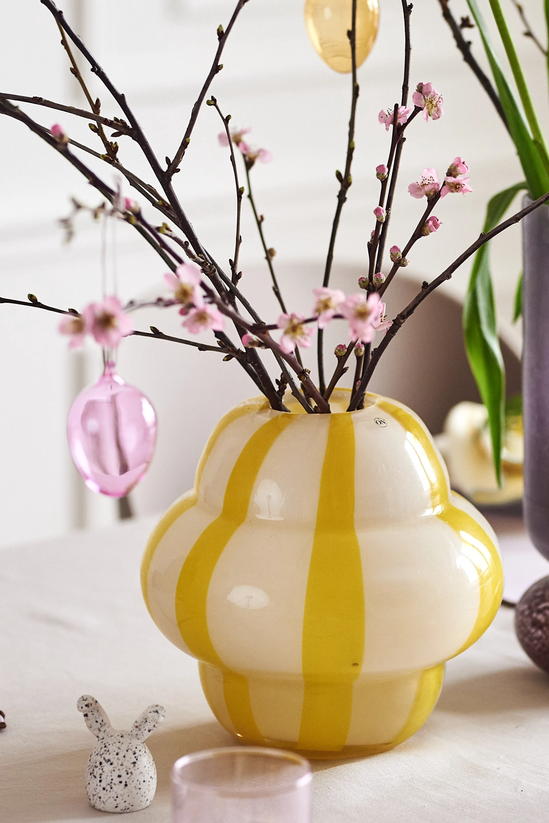 Create a festive Easter table setting in spring pastels with Iittala's colourful glass eggs in a beautiful Easter branch that is in the Curlie vase from By On.